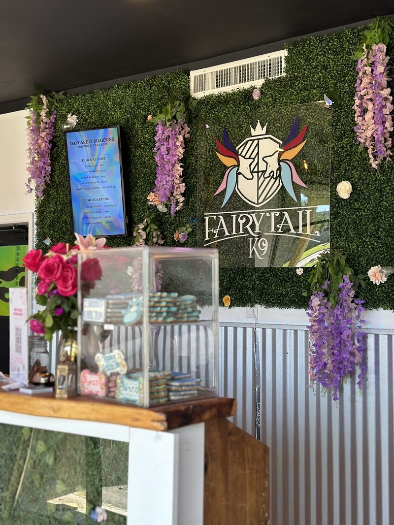 The studio frontage inside the premises: faux-grass wall, wisteria garlands and a glass retail display cabinet on a wooden counter (crop out the burned-in words)